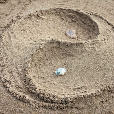 A yin yang design sculpted in sand with seashells at Isla Canela beach, Spain.